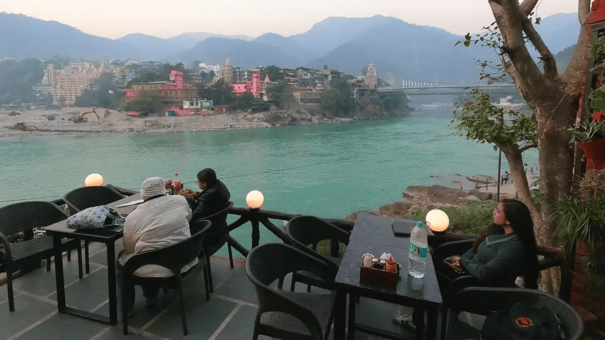 Sunlit riverside cafe interior with warm wood tones and artisan coffee — Rishikesh cafe culture near Sharnam on the Ganges