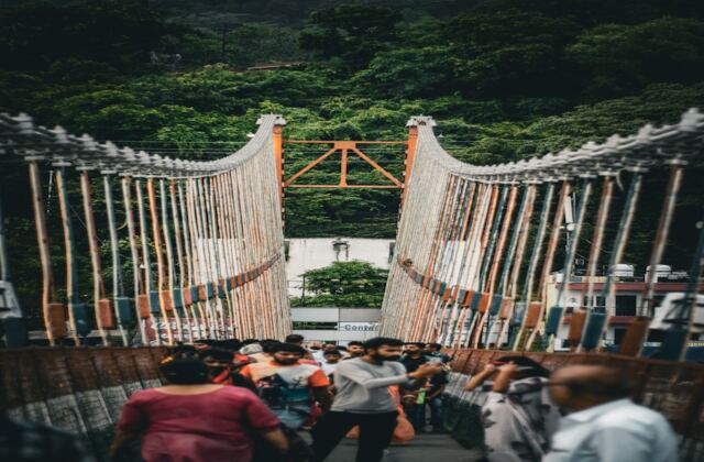 Laxman Jhula iron suspension bridge over the Ganges with temple spires, Rishikesh — close to Sharnam on the Ganges