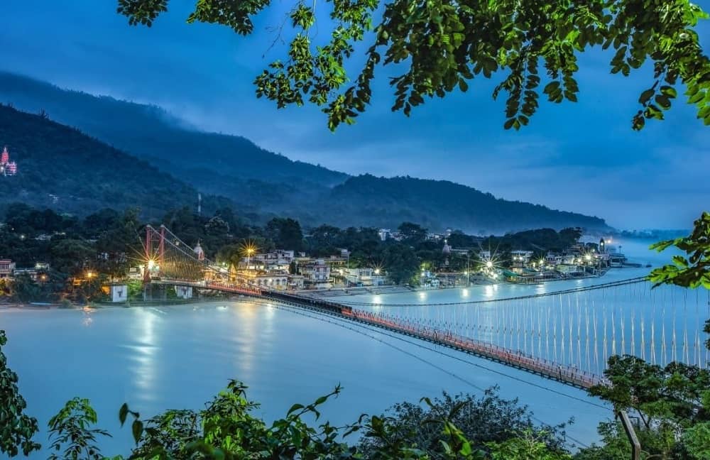 Ram Jhula pedestrian suspension bridge spanning the Ganges at dusk, Rishikesh — near Sharnam on the Ganges