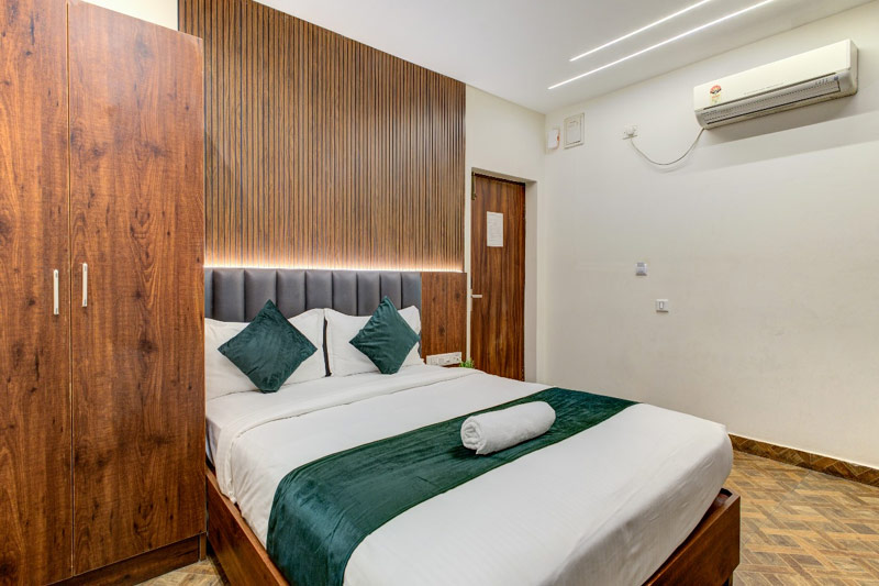 Deluxe Comfort Room — king bed with warm wooden finishes and soft accent lighting — Sharnam on the Ganges, Rishikesh